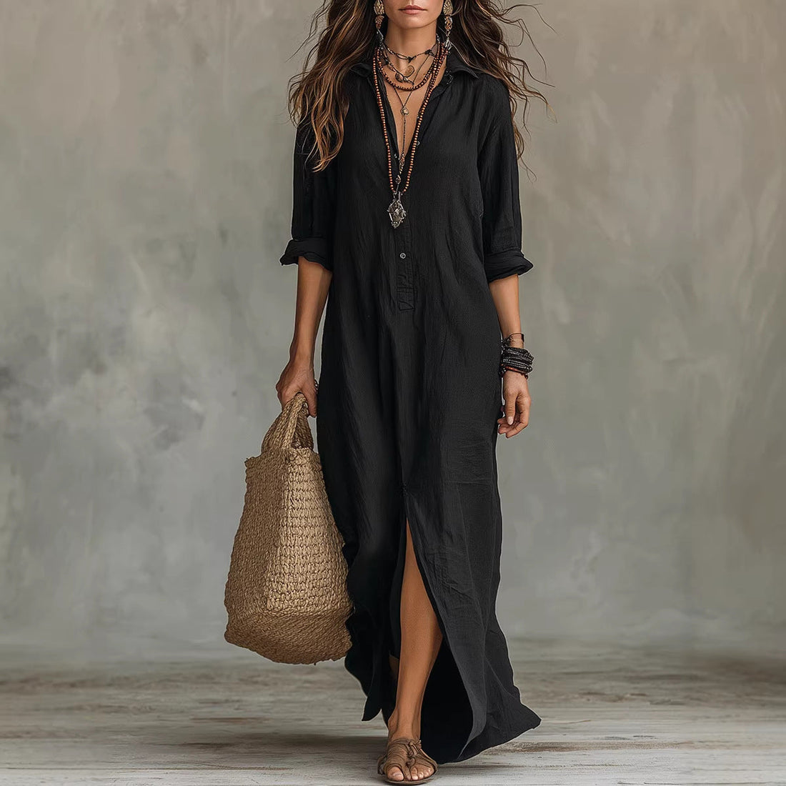 Woman wearing an elegant black long sleeve lapel collar beach maxi dress with a slit-detail during a summer sunset.