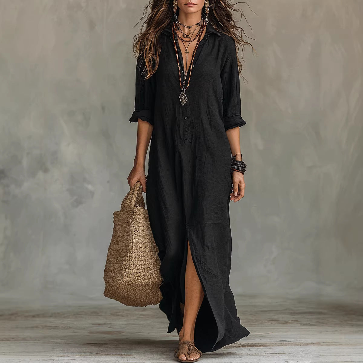 Woman wearing an elegant black long sleeve lapel collar beach maxi dress with a slit-detail during a summer sunset.