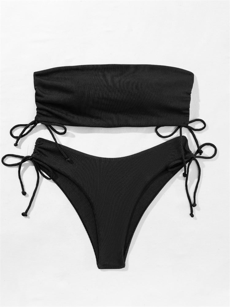 Front view of a model wearing a premium black minimalist ribbed tube bikini set with adjustable drawstring top and side tie bottoms.